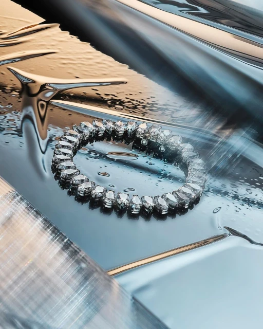 Close-up of a crystal bracelet on a wet metallic surface. Abstract composition featuring reflective surfaces and clear water droplets.