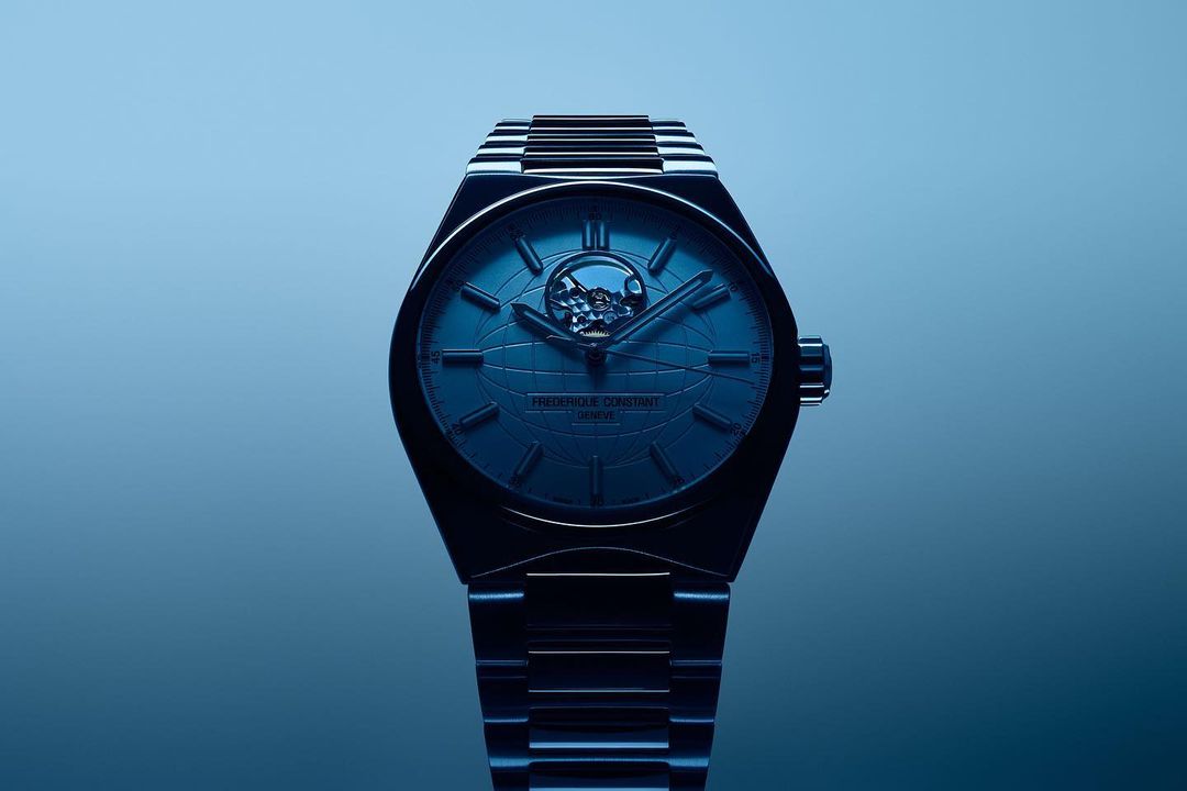 Close-up studio shot of a Frederique Constant watch with a blue dial and silver band, displaying the intricate inner workings of the timepiece.