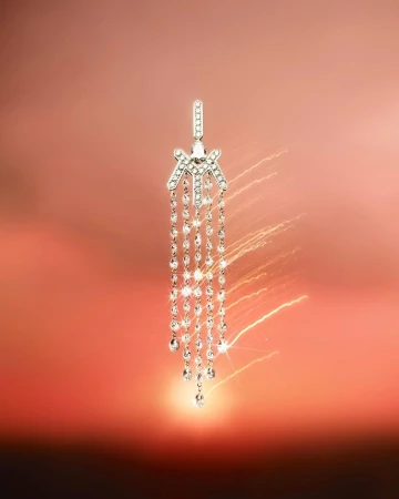 Elegant silver earring with cascading crystals sparkles against a soft orange gradient background, exuding luxury and sophistication.
