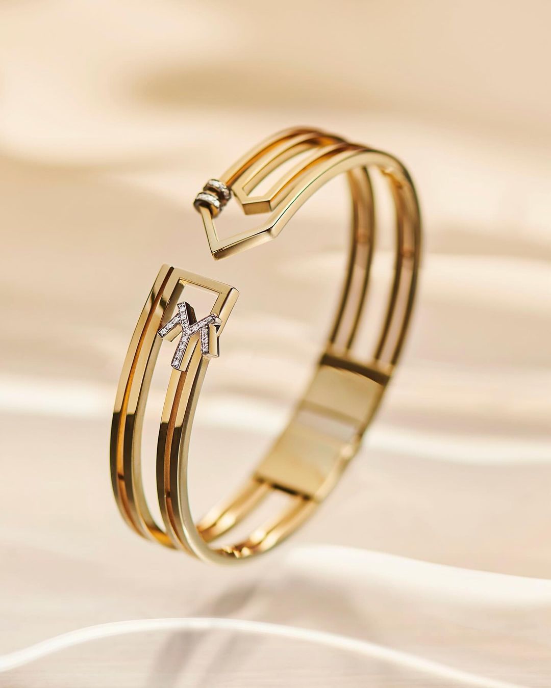 Elegant gold and diamond bracelet on a soft, cream-colored fabric backdrop, highlighting luxury jewelry and fine craftsmanship.