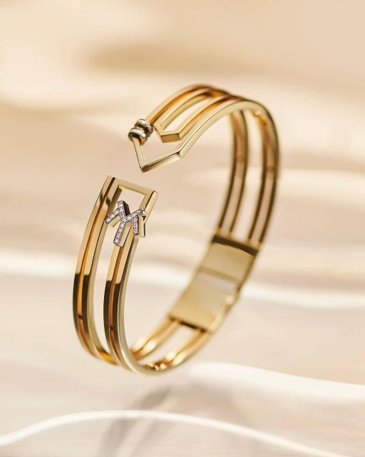 Elegant gold and diamond bracelet on a soft, cream-colored fabric backdrop, highlighting luxury jewelry and fine craftsmanship.