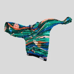 Colorful patterned garment with accordion pleats floating against a plain light gray studio background.