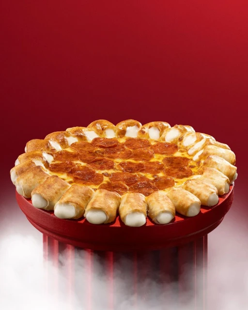 A pepperoni pizza with stuffed cheese crust on a red plate, presented against a gradient dark-red background with diffused lighting.