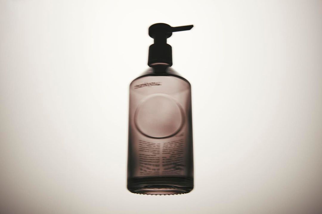 Studio shot of a dark glass bottle with a pump dispenser against a bright white background, emphasizing its simple design and functionality.