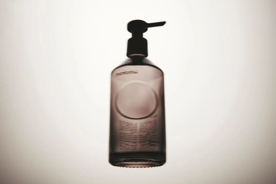 Studio shot of a dark glass bottle with a pump dispenser against a bright white background, emphasizing its simple design and functionality.