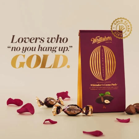 Whittaker's Cocoa Pods box surrounded by chocolate candies and rose petals, product shot for Valentine's Day gifting concept.