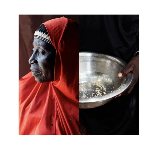 Portrait of an elderly African woman in a red headscarf with a metal bowl held by a dark-skinned person against a dark background.