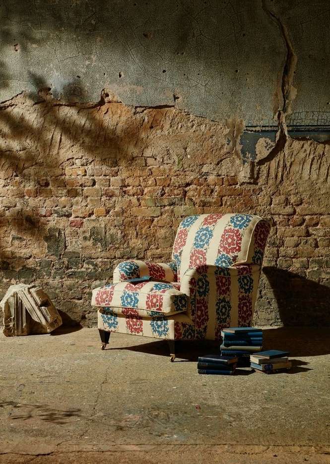 Armchair with floral pattern in aged room, illuminated by natural light, creating a vintage and cozy atmosphere.