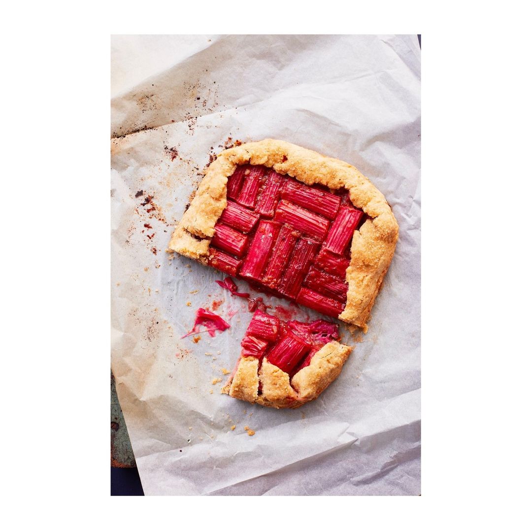 Overhead shot of a rhubarb galette on parchment paper, showcasing the pastry and the bright pink rhubarb filling.