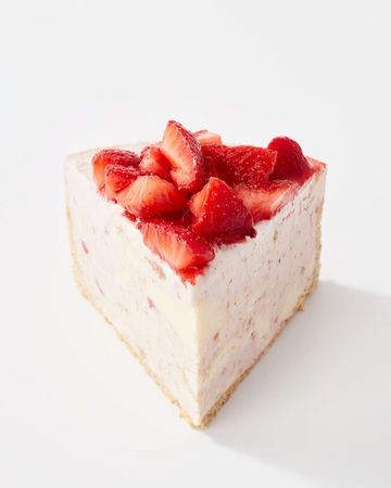 Delicious slice of strawberry cheesecake featuring a creamy filling, graham cracker crust, and topped with fresh, sliced strawberries.