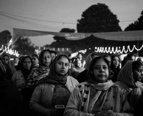 Black and white portrait of women in headscarves gathered in an outdoor night setting by photographer Yushy Pachnanda