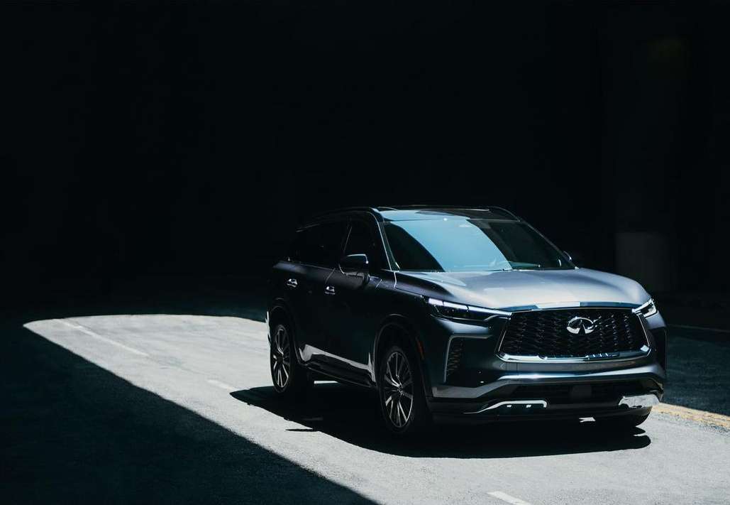 Sleek gray SUV under dramatic lighting on an asphalt road. The vehicle's modern design is highlighted against a dark background.