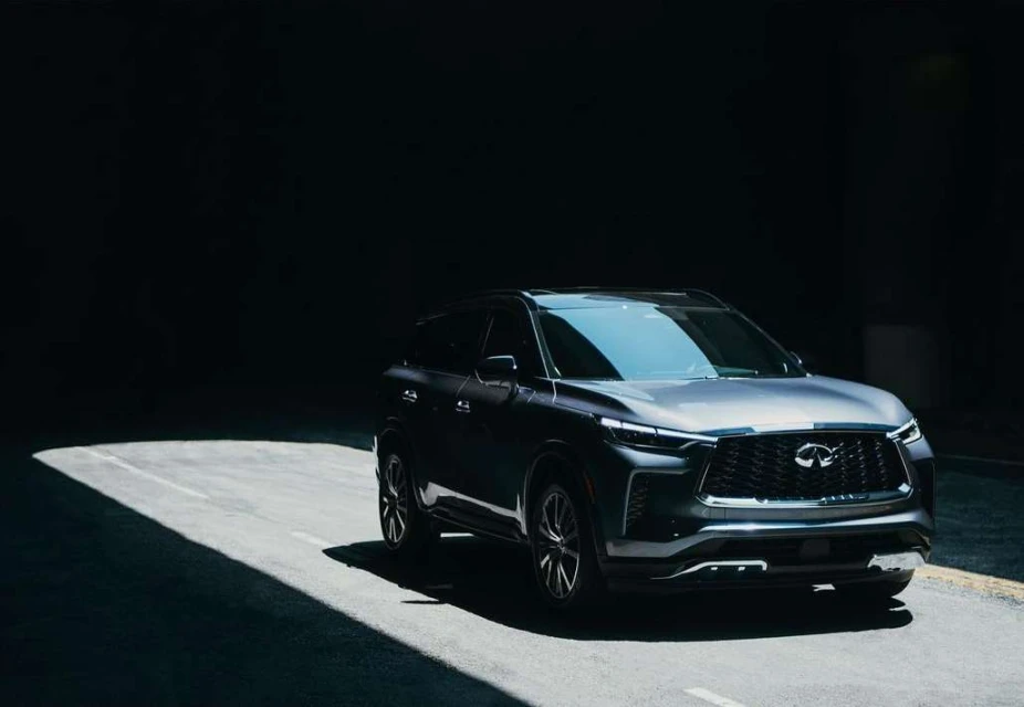 Sleek gray SUV under dramatic lighting on an asphalt road. The vehicle's modern design is highlighted against a dark background.