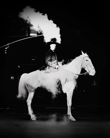 A person in formal attire riding a white horse, with a large cloud of smoke emanating from the head, set against a dark background.