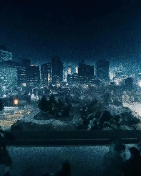 City skyline at night featuring modern buildings with illuminated windows, creating a striking urban cityscape under a dark sky.