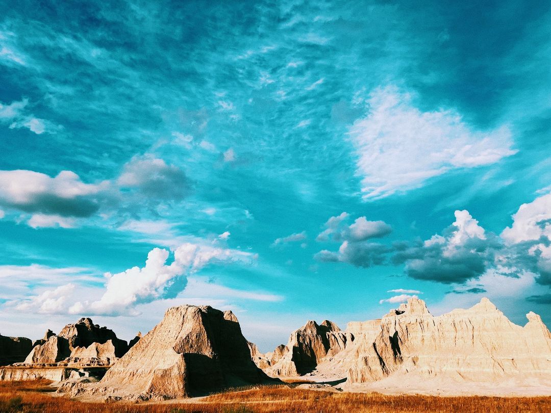 Badlands National Park landscape featuring buttes and prairie with blue sky and clouds in South Dakota, United States.