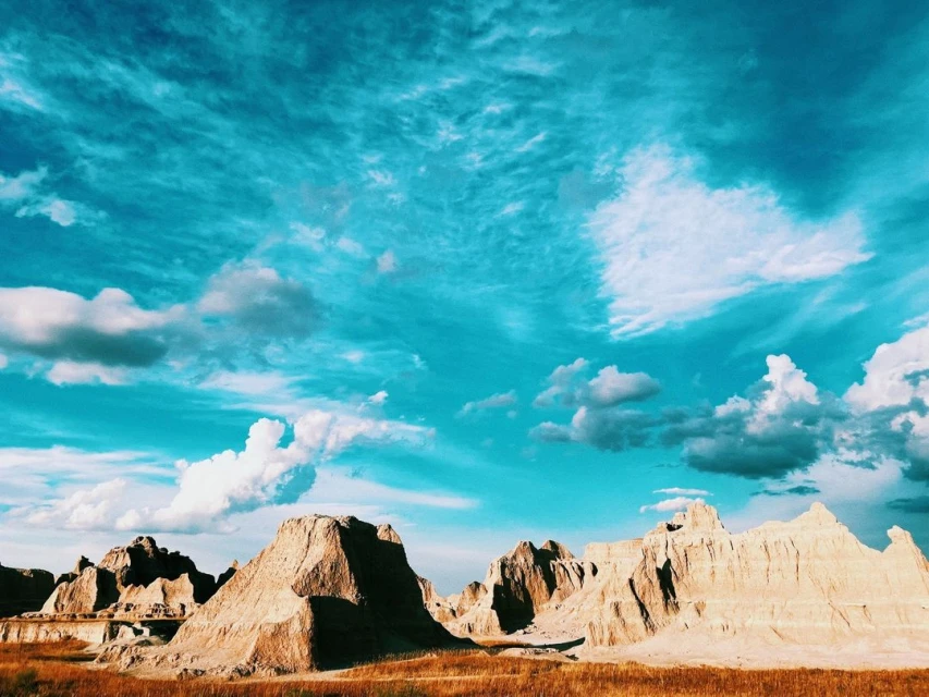 Badlands National Park landscape featuring buttes and prairie with blue sky and clouds in South Dakota, United States.