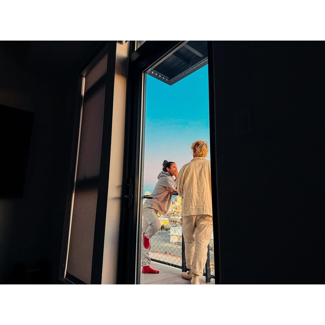 Two people standing on a balcony framed by an open doorway, photographed by Zach Anderson in San Francisco.