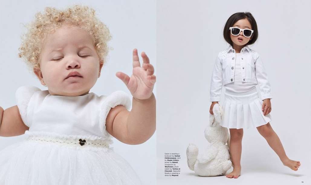 Two young children in all-white outfits posing in a studio. One child wears sunglasses and holds a plush rabbit toy.