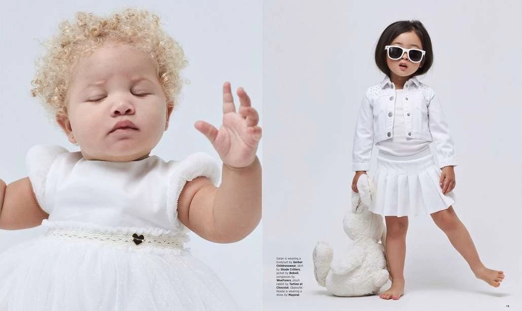 Two young children in all-white outfits posing in a studio. One child wears sunglasses and holds a plush rabbit toy.