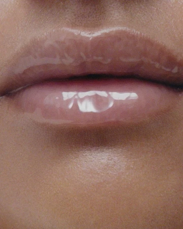 Close-up shot of a woman's lips with glossy pink lip gloss, emphasizing beauty and makeup in a skincare advertisement.
