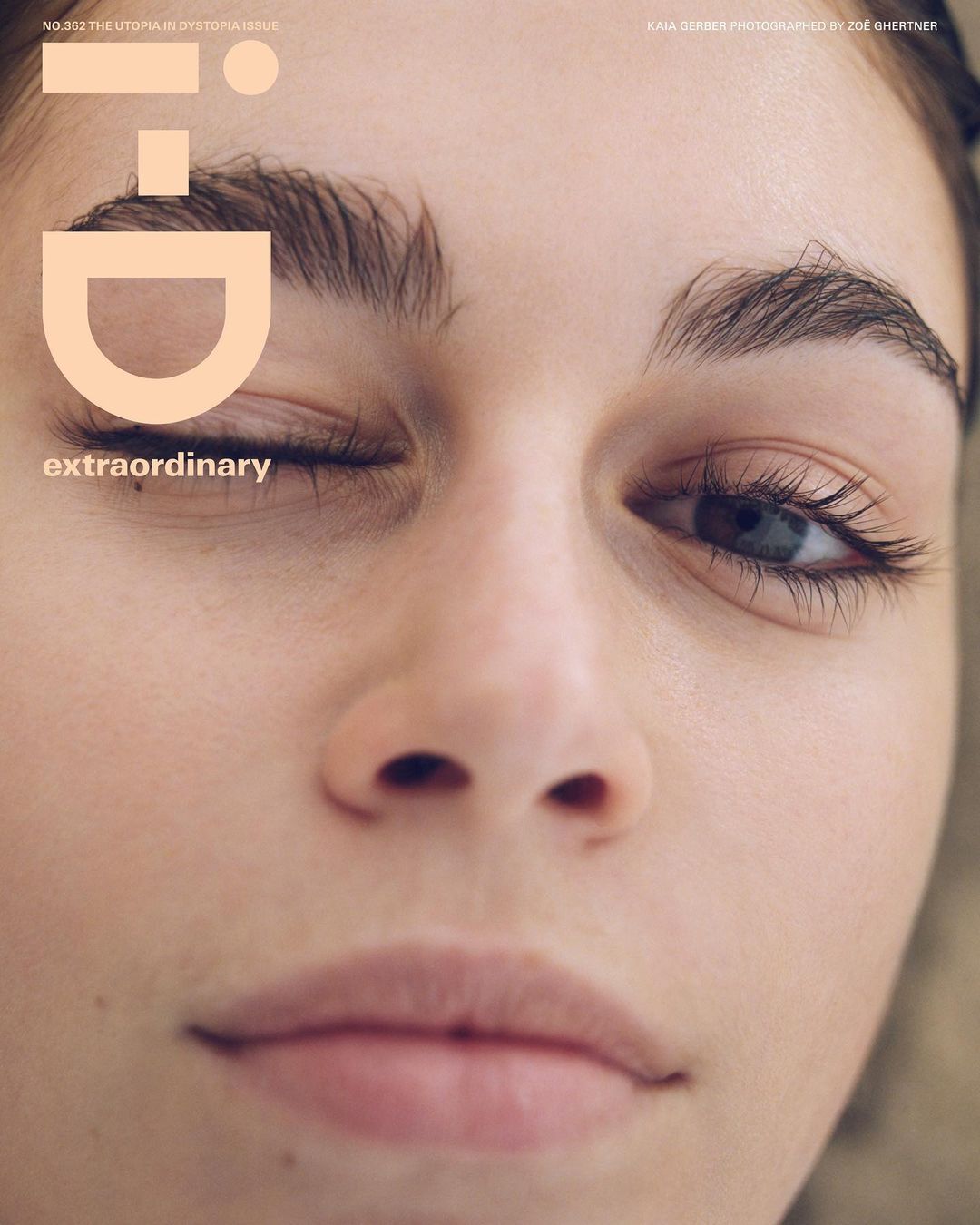 Close-up studio portrait of a fair-skinned young woman with makeup; one eye closed and looking at the camera; 'i-D' magazine cover.