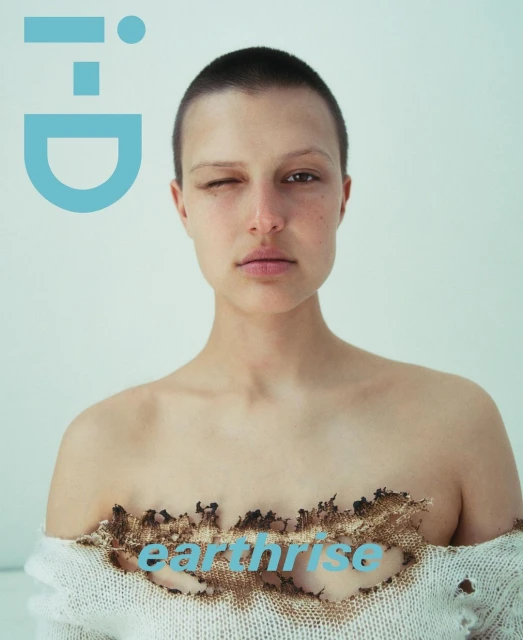 Magazine cover featuring a portrait of a woman with a shaved head, wearing a ripped sweater, set against a white backdrop.