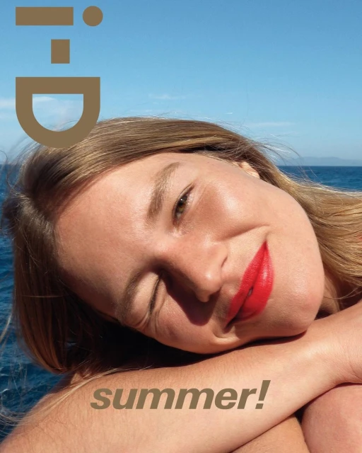 Magazine cover featuring a smiling woman with bright red lipstick against a backdrop of blue sky and ocean, summer theme. Fashion.