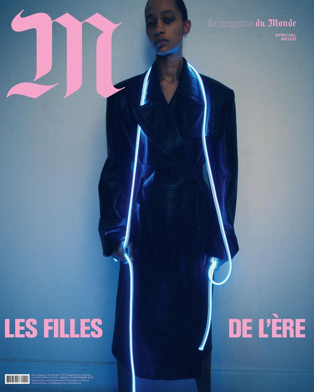 Magazine cover featuring a Black female fashion model in a black coat with neon accents, against a gradient blue backdrop.