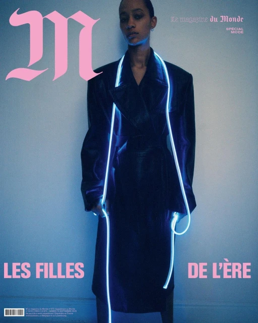 Magazine cover featuring a Black female fashion model in a black coat with neon accents, against a gradient blue backdrop.