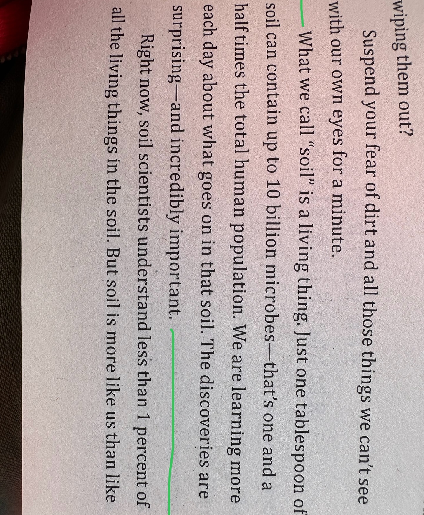 Close-up of a page from a book with text about soil science, highlighting the importance of soil and its microscopic contents.
