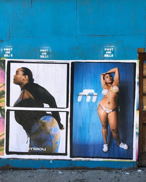 Fashion posters on a blue wall feature models, one in swimwear and the other in a skirt and top, promoting clothing brands.