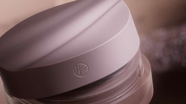 Close-up shot of a light purple cosmetic container with a circular logo on the lid, showcasing beauty and skincare product.