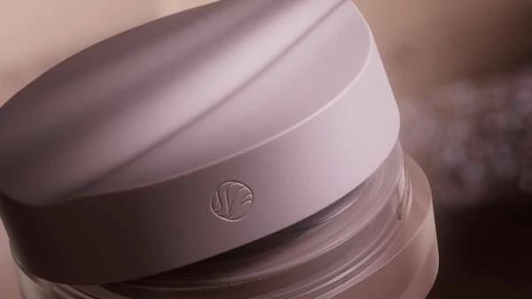 Close-up shot of a light purple cosmetic container with a circular logo on the lid, showcasing beauty and skincare product.