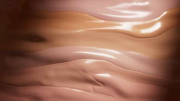 Swatches of makeup foundation in pink, tan, and brown tones, creating a layered effect with a smooth, glossy texture.