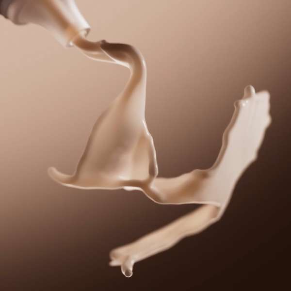 Abstract studio shot of viscous liquid flowing from a white tube against a tan backdrop, creating dynamic shapes and movement.