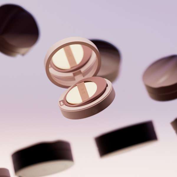 Floating shot of a makeup compact with pale pink case and sponge applicator, surrounded by additional compacts against a light background.