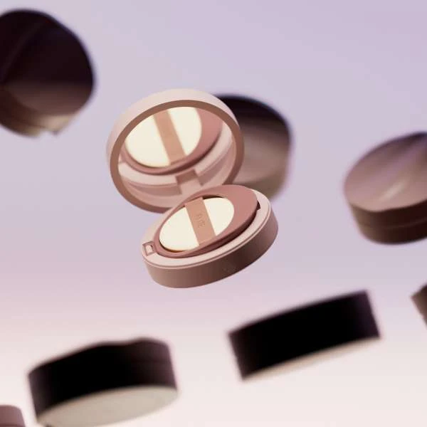 Floating shot of a makeup compact with pale pink case and sponge applicator, surrounded by additional compacts against a light background.