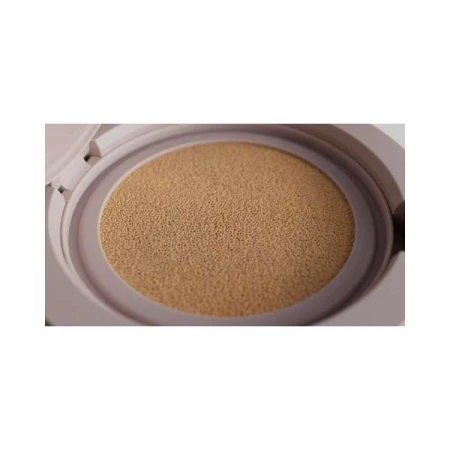 Tan-colored cushion compact case, open, showing the beige-colored sponge insert, in a studio setting against a white background.