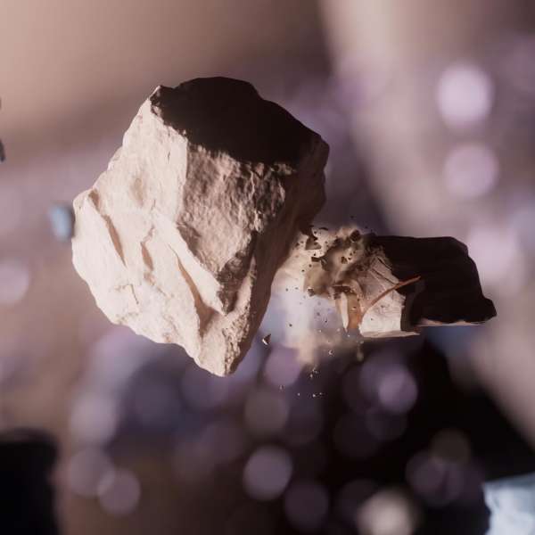 Abstract image featuring a jagged, light-brown rock suspended mid-air against a blurry background with a scattering of light and dust particles.