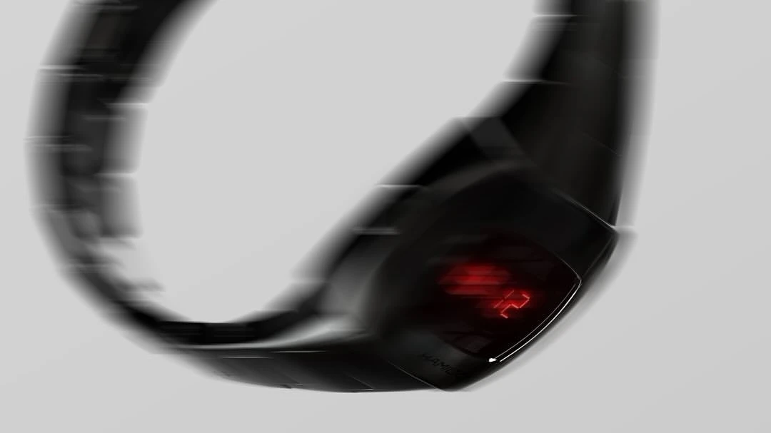Sleek black wearable device with a glowing red digital display, blurred in motion against a plain light gray background.