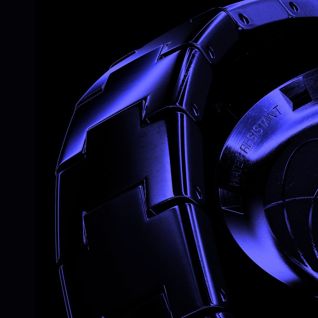 Close-up of a metallic wristwatch band with blue lighting against a black background, emphasizing its design and texture.