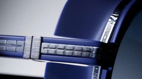 Extreme macro close-up of blue and silver metallic eyewear frames with intricate engraved textures.