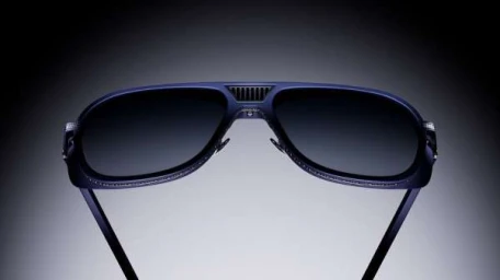Dark aviator sunglasses with gradient lenses and textured temples against a smooth grey gradient background.