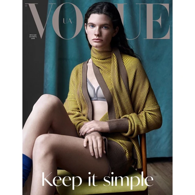 Fashion magazine cover featuring a female model in a yellow and brown knit cardigan and bra sitting on a green chair in a studio.