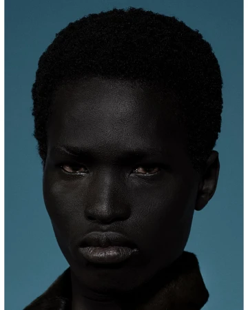 Close-up studio portrait of an adult with dark complexion looking at the camera, showcasing a modern fashion beauty aesthetic.