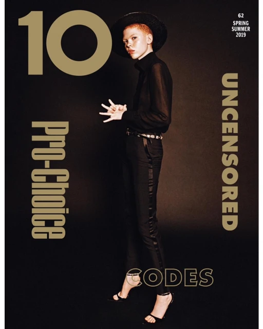 Fashion magazine cover featuring a woman in black formalwear and a wide-brimmed hat, set against a dark backdrop with overlaid text.