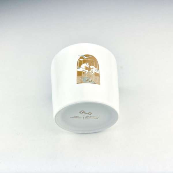 White ceramic pot featuring a gold illustration of horses on a white background, angled view.