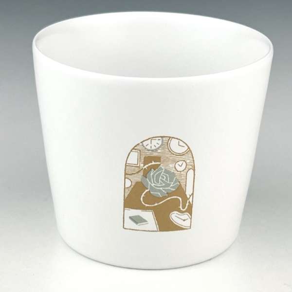 Close-up of a white ceramic mug adorned with a detailed gold and gray illustration of a rose, book, and clocks on a table.