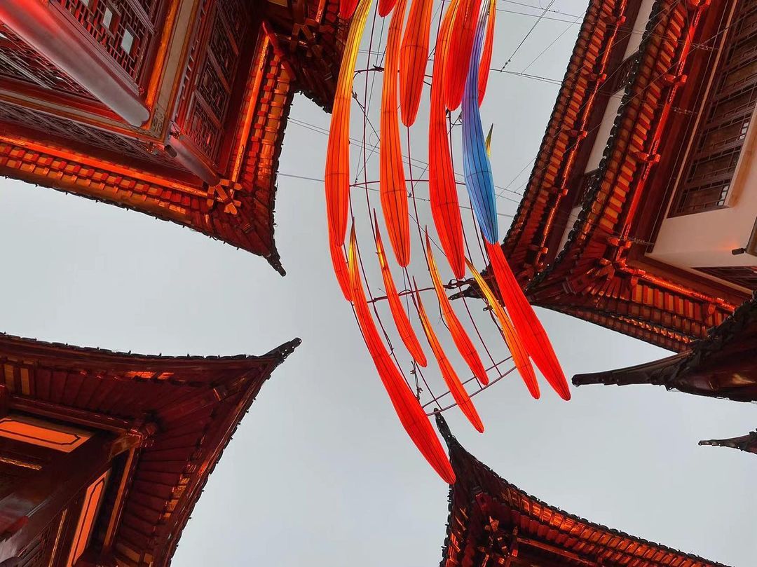 Low angle view of traditional Chinese buildings with red roofs and decorative hanging lanterns creating a festive atmosphere.